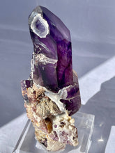 Load image into Gallery viewer, Goboboseb Mountains. Erongo Region, Namibia.  Weight: 180.5 grams  Dimensions: L 5 x W 4 inches x 2.75 inches  Holy smokes this is such an insane piece. Pockets of chalcedony adorn this gorgeous Amethyst point. This baby glows bright green under short wave. Theres pieces that come along once in a lifetime and we consider this to be one of them. Custom stand is included.
